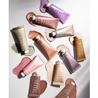 Assorted rms beauty cream tubes with swatches on a white background.