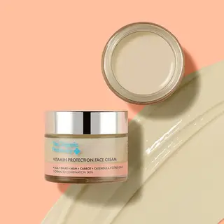 Vitamin Protection Face Cream jar and open lid on peach background. Cream spread nearby.
