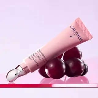 Pink tube of Caudalie Resveratrol Lift Eye Gel on red grapes.