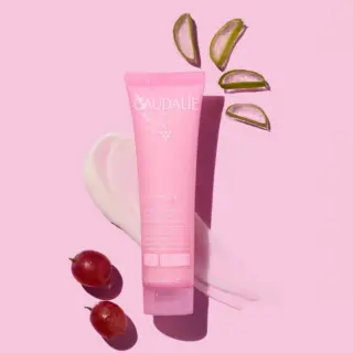 Pink Caudalie VinoHydra gel moisturiser with aloe slices and grapes on pink background.