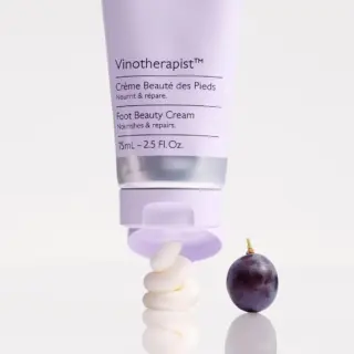 Vinotherapist Foot Beauty Cream tube with cream swirl and a grape on a white surface.