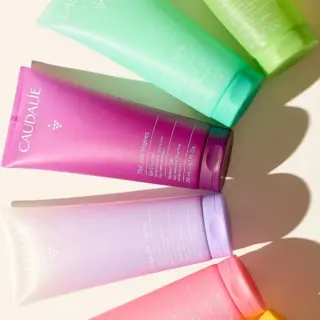 Colourful Caudalie shower gel tubes arranged on a light surface.