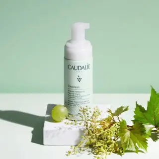 Caudalie Vinoclean foaming cleanser with grape and vine leaves on a white surface.