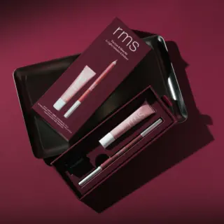 RMS lip kit with gloss, pencil, and sharpener in a dark red box on a matching background.