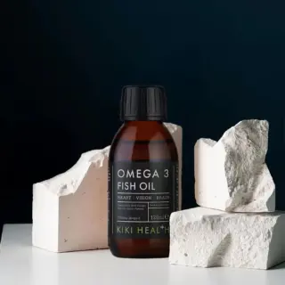 Omega 3 Fish Oil bottle with white rocks, dark background.