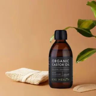 Organic castor oil bottle, 250ml, with loofah, plant, and comb on a beige background.