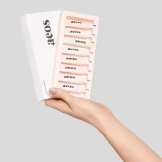 Hand holding aeos skincare set with six tubes in a white box.