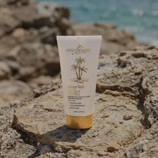 Eco by Sonya Glory Veil SPF 50+ sunscreen on rocky beach background.