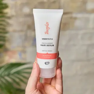 Hand holding Green People Protein-Boost Hair Serum tube.