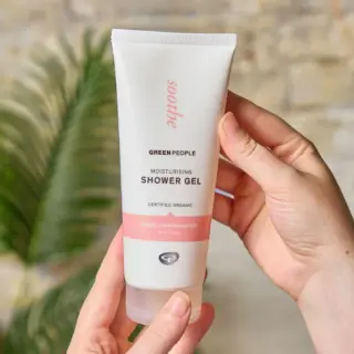 Hands holding Green People moisturising shower gel tube.