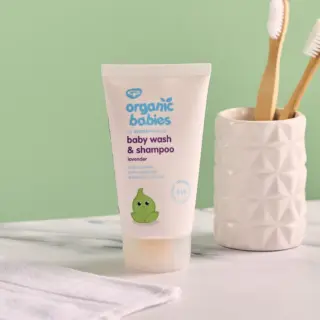 Organic Babies lavender baby wash tube on a bathroom counter with toothbrushes.