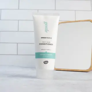 Green People Daily Aloe Conditioner tube on tiled bathroom counter.