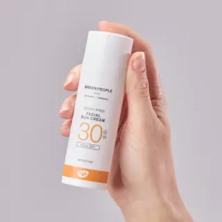 Hand holding Green People SPF 30 scent-free facial sun cream bottle.
