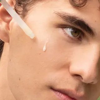 Dropper applying serum to a person's cheek.