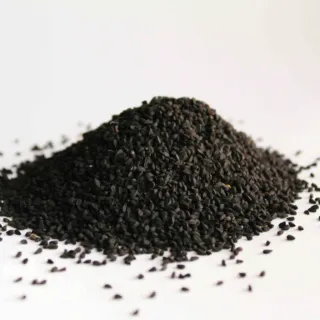 Pile of black seeds scattered on a white surface.