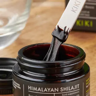 Himalayan Shilajit jar with a spatula dipped in dark paste.