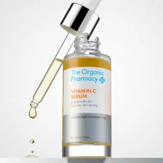 The Organic Pharmacy Vitamin C Serum with dropper and liquid droplet.