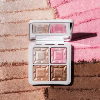 Makeup palette with four shades on textured background. "rms beauty" text on the case.