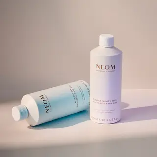 Two NEOM magnesium bath milk bottles on a light surface.