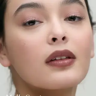 Close-up of a person with natural makeup. Text: "Mallo Coast".