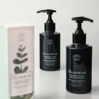 Two bottles of Olverum Firming Body Moisturiser with a box in the background.