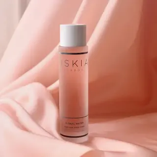 Pink bottle of Oskia London Floral Water on soft pink fabric background.