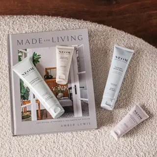 Neom hand balms on a book titled "Made for Living" by Amber Lewis on a textured surface.