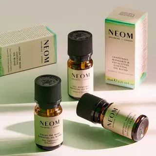 Three NEOM essential oil bottles with boxes, featuring blends like grapefruit and eucalyptus.