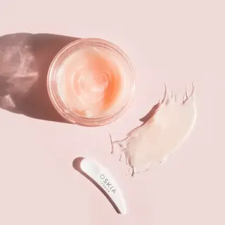 Open jar of pink cream with a white spatula labelled "O.S.K.I.A London" on a pink background.
