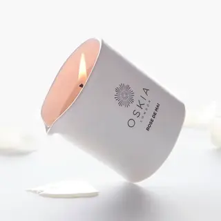 White candle labelled "OSKIA London Rose de Mai" with petals around.