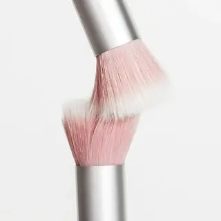 Two pink makeup brushes with silver handles touching bristles.