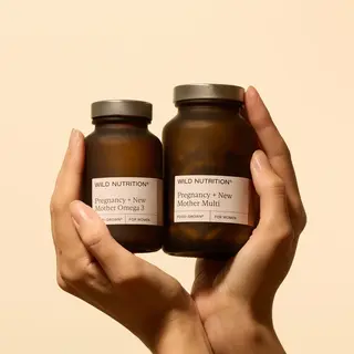 Two hands holding Wild Nutrition supplements for pregnancy and new mothers.