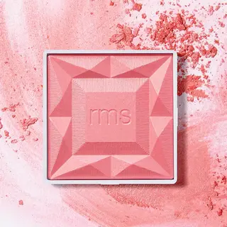 Pink blush compact with "rms" embossed, surrounded by loose powder.