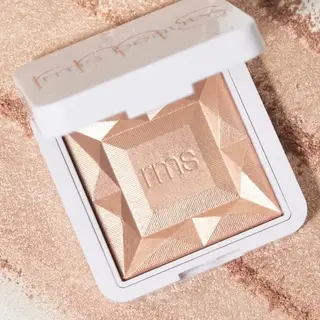 Open compact with embossed "rms" on a textured, shimmering powder surface.
