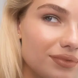 Close-up of a woman's face with smooth skin and nude lipstick. Text: "JAYNE".