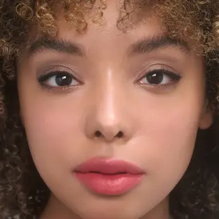 Close-up of a person with curly hair and pink lipstick. Text: "MIRANDA".