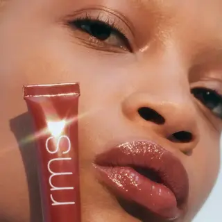 Person with glossy lips holding RMS Liplights tube. Text: "RHAPSODY".