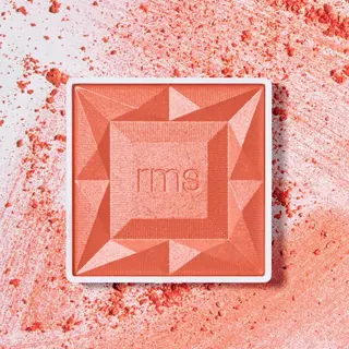 Coral blush compact with "rms" logo, surrounded by scattered powder.