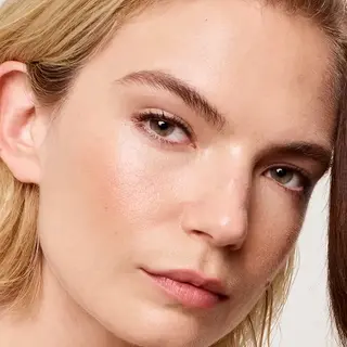 Close-up of a person with clear skin and light hair, looking towards the camera.