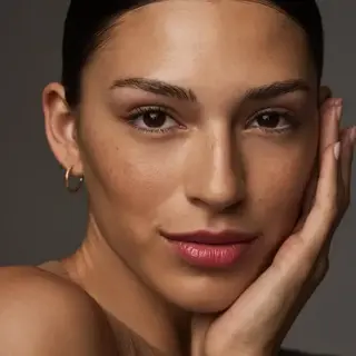 Person with smooth skin, hand on face, wearing hoop earring. Text: "SAND" in corner.