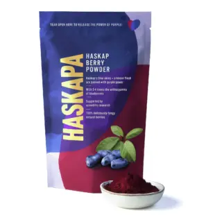 Haskapa berry powder pouch with bowl of red powder and fresh berries.