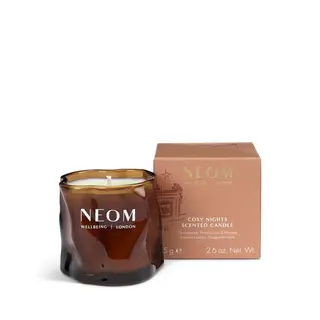 Brown glass candle with "NEOM Wellbeing London" text, next to a matching box.