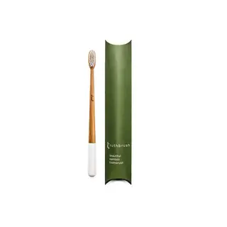 Bamboo toothbrush with white handle next to green packaging labelled "truthbrush".