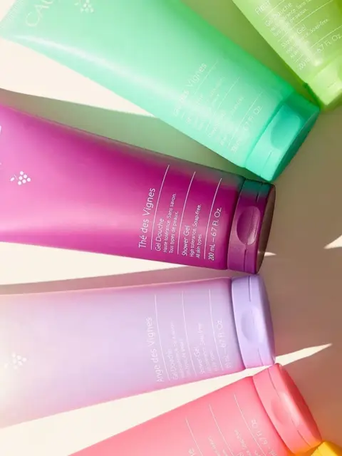 Colourful Caudalie shower gel tubes arranged on a light surface.