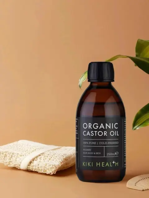 Organic castor oil bottle, 250ml, with loofah, plant, and comb on a beige background.