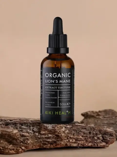 Brown dropper bottle labelled "Organic Lion's Mane Extract Tincture" on wooden surface.