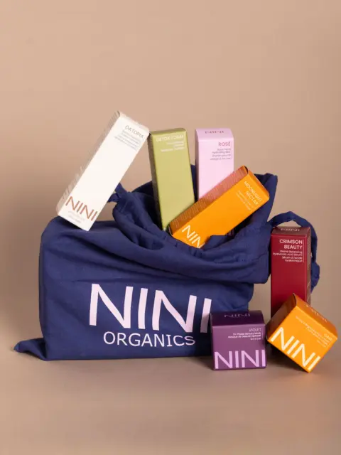 NINI Organics products in a blue bag, including boxes labelled Oat Foam, Detox Foam, and Crimson Beauty.