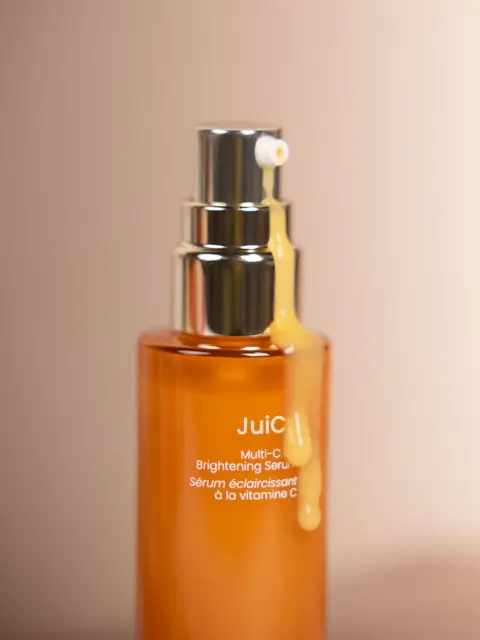 Orange serum bottle with silver pump, labelled "JuiC Multi-C Brightening Serum".