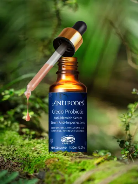 Antipodes Credo Probiotic Serum bottle with dropper in a lush green setting.