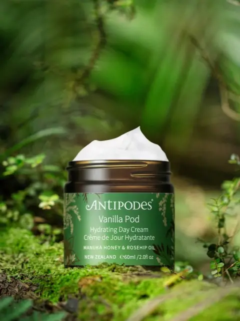 Antipodes Vanilla Pod Day Cream jar on a mossy forest floor.